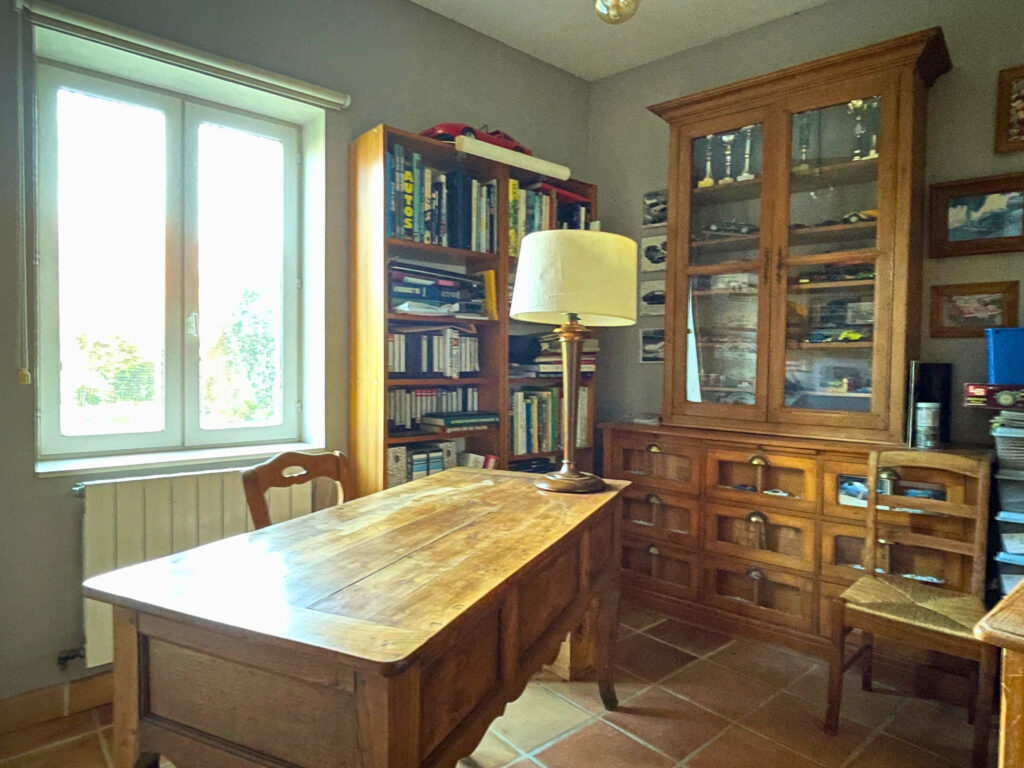 Bureau aménagé dans la maison principale, avec lumière naturelle et vue sur l’extérieur, idéal pour le télétravail ou un espace lecture