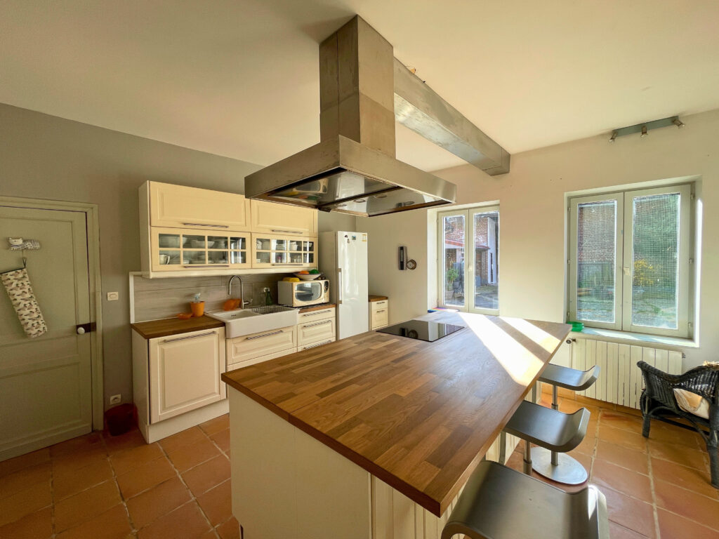 Vue d’ensemble de la cuisine équipée de la maison, avec grand îlot central, nombreux rangements et belle luminosité