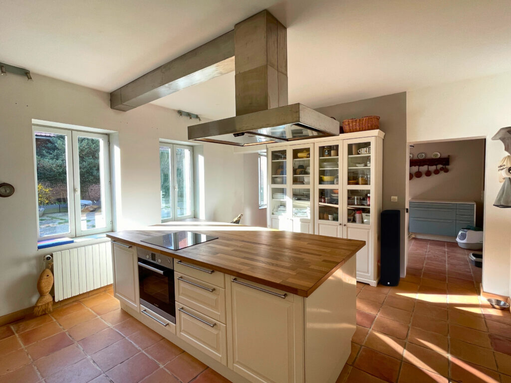 Zoom sur l’îlot central de la cuisine, avec coin repas intégré et accès direct à la salle à manger attenante