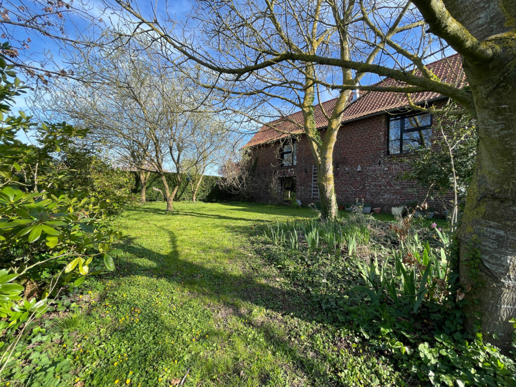 Façade sud-ouest de la propriété avec verger attenant, orientation ensoleillée et vue dégagée sur les arbres fruitiers