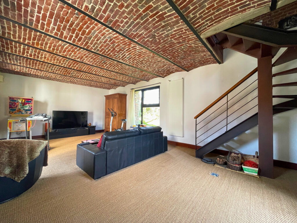 Salon situé au rez-de-chaussée, espace cocooning idéal pour un coin télévision ou détente, avec lumière naturelle et accès direct à la salle à manger
