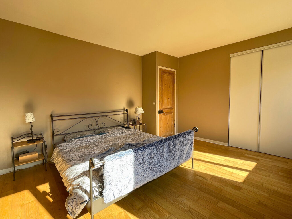 Chambre principale de la maison, d’une surface de 18 m², avec grande fenêtre, lumière naturelle et vue dégagée sur l’extérieur
