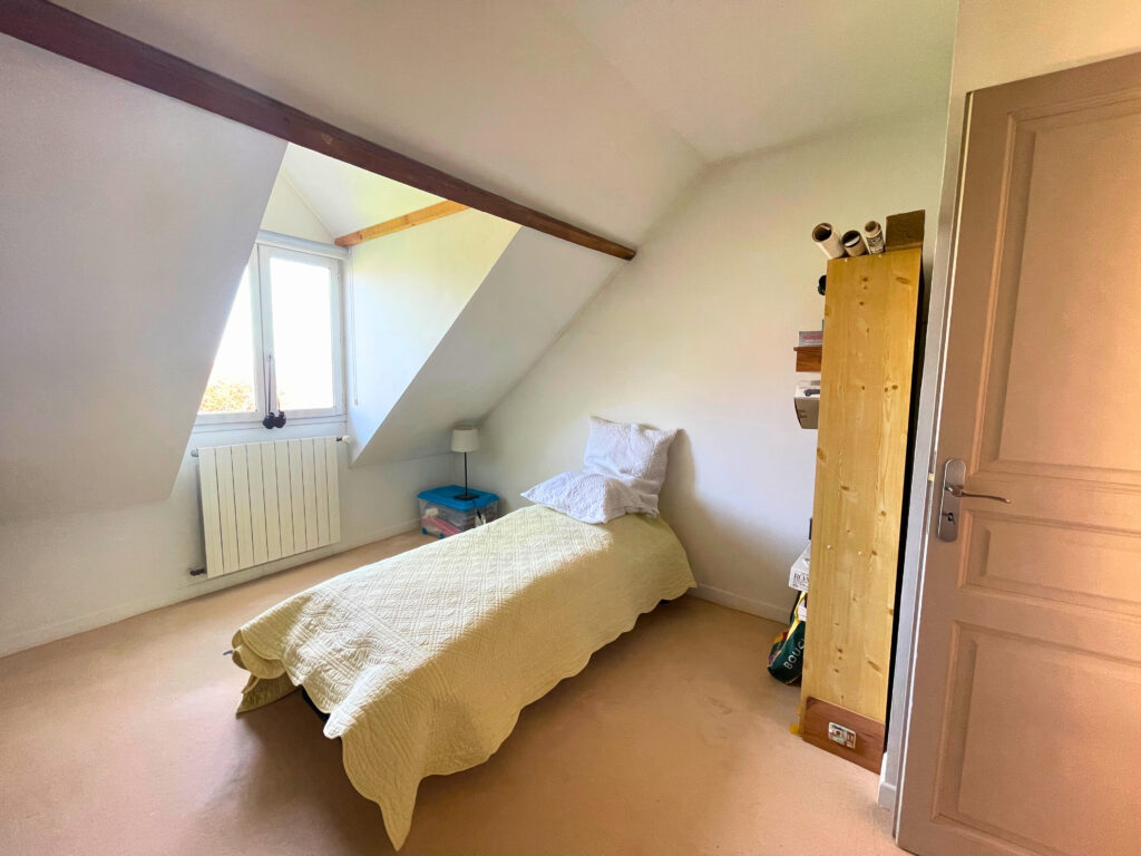 Chambre de la maison avec fenêtre sur jardin, ambiance calme et moquette au sol, idéale pour un enfant