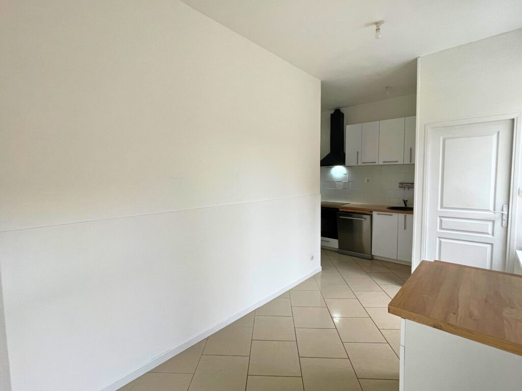 Vue d’ensemble de la cuisine équipée et du séjour, maison rénovée à Raimbeaucourt, carrelage clair et murs blancs