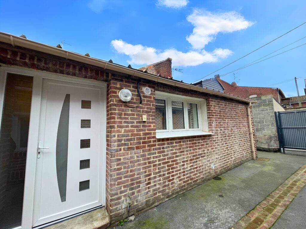 Studio indépendant de 33 m² en briques rouges avec porte PVC blanche, accès par la voyette, à Raimbeaucourt