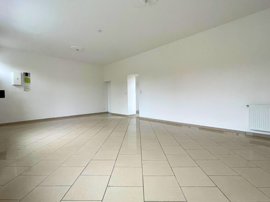 Grand séjour traversant de 36 m², carrelage clair et murs blancs, maison rénovée à Raimbeaucourt