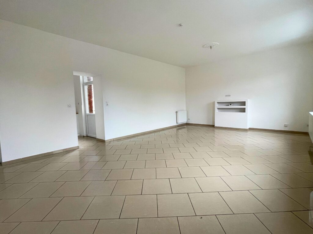 Séjour lumineux donnant sur la cuisine indépendante, maison rénovée à Raimbeaucourt, carrelage beige et murs blancs