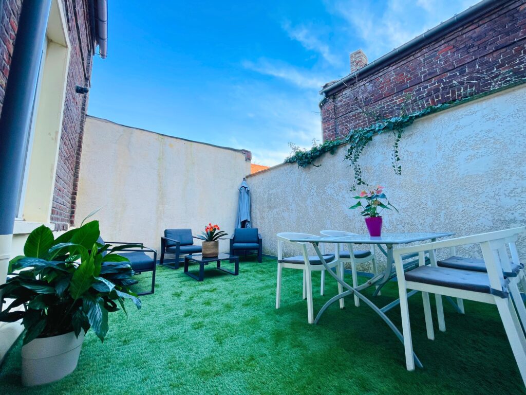 Cour close, transformée ici par une mise en scène simple : mobilier d’extérieur, tapis, végétaux en pot et éclairages. Une projection réaliste montrant le potentiel de cet espace pour les beaux jours.